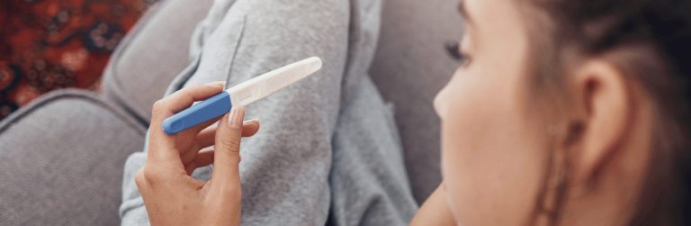 Close-up of a woman looking at a pregnancy test, unsure of the outcome