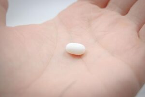 A pill in someone's hand representing a woman considering taking missed period pills.